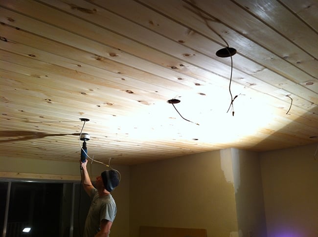installing lights and speakers on a wood plank ceiling