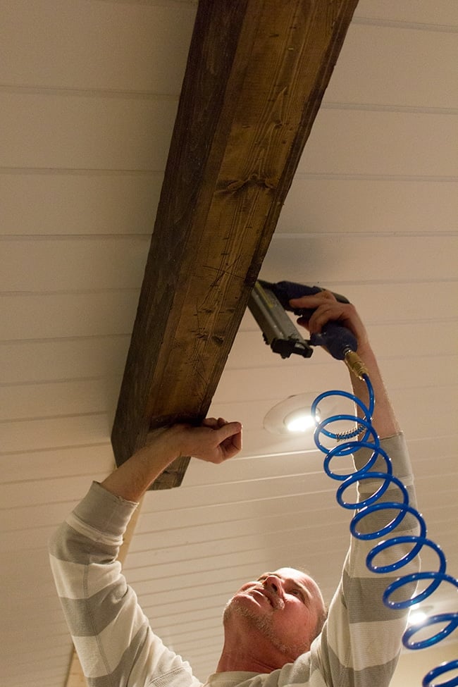 nailing wood beams onto a ceiling