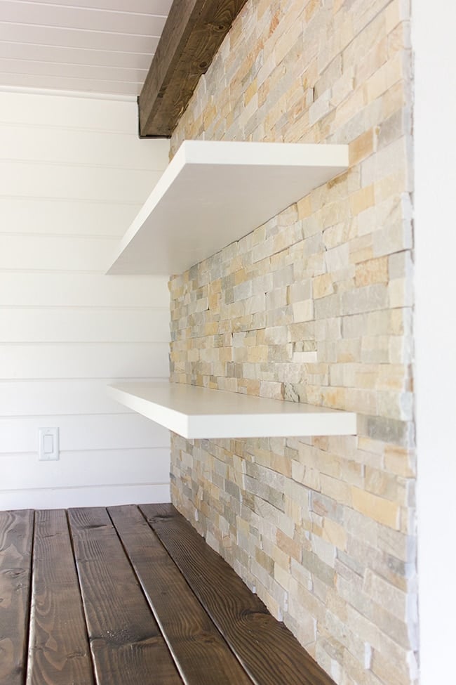 custom floating shelves on a stacked stone wall