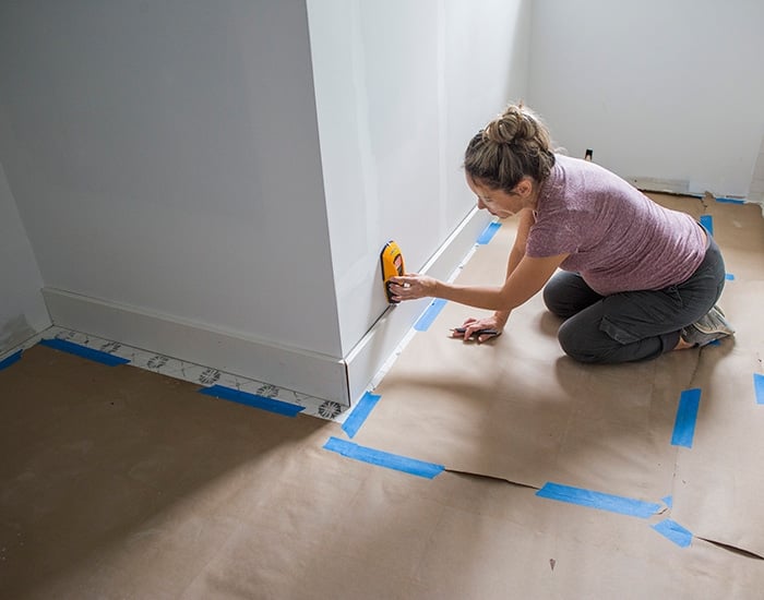 using a stud finder to find studs along the baseboard