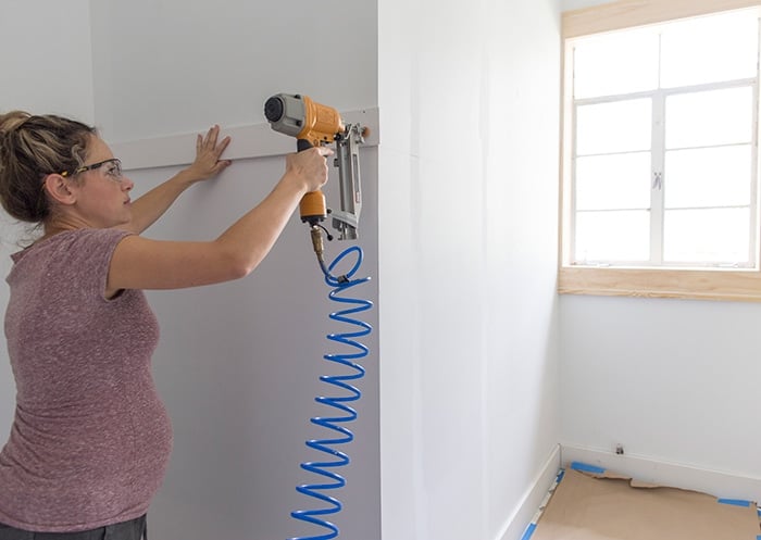 nailing a horizontal board onto the wall for board and batten