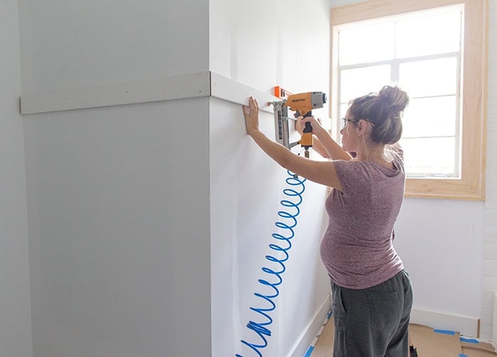 nailing a horizontal board onto the wall for board and batten