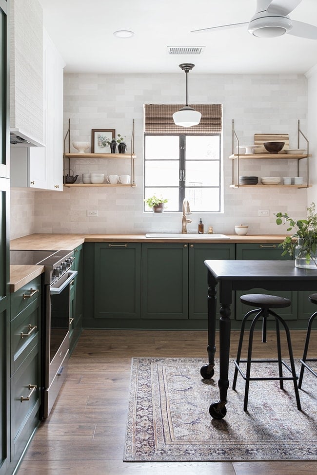 kitchen with green lower cabinets, white tile and open shelving
