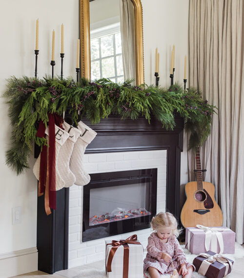 fireplace with christmas garland, stockings and gifts
