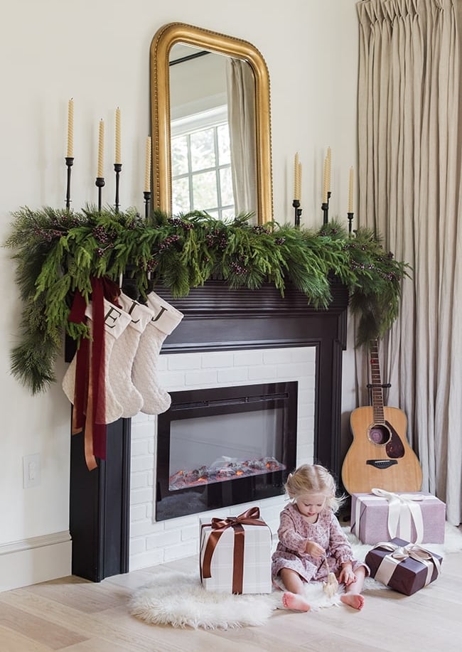 fireplace with christmas garland, stockings and gifts