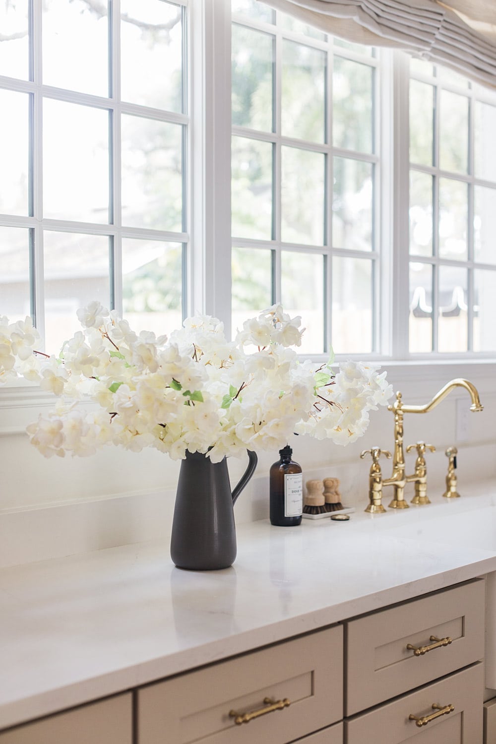 faux white cherry blossoms in vase on kitchen counter