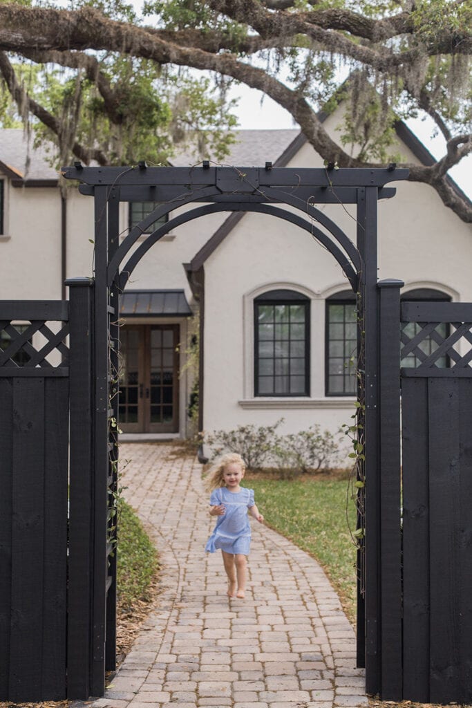 girl running under black fence arbor