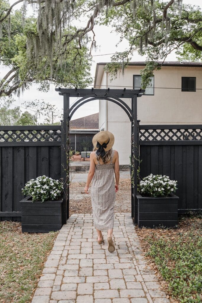 girl walking under black fence arbor