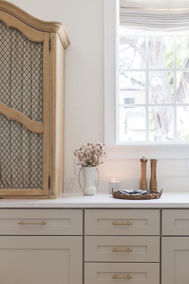 kitchen with mushroom cabinets, gold hardware and a lit candle