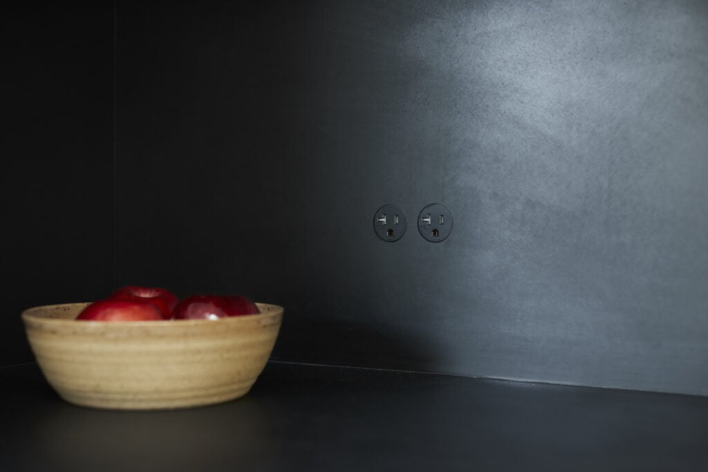 bocci hidden self contained outlet receptacles on a black kitchen backsplash wall
