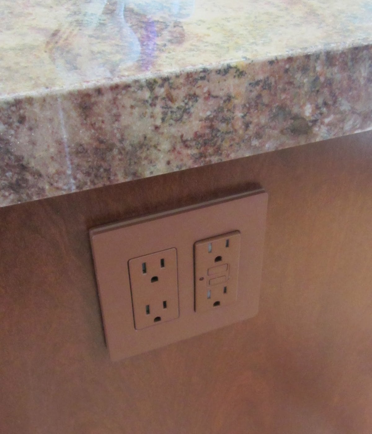 brown outlet receptacle and wall plate in a dark wood kitchen island