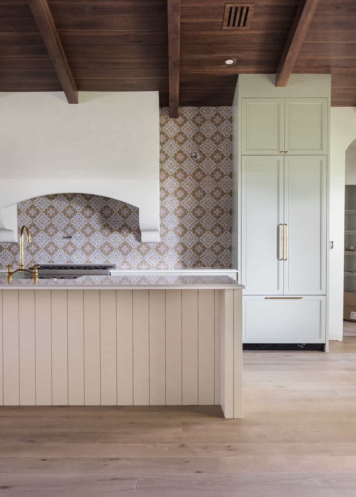 spanish style kitchen with sage green cabinets and creamy white island