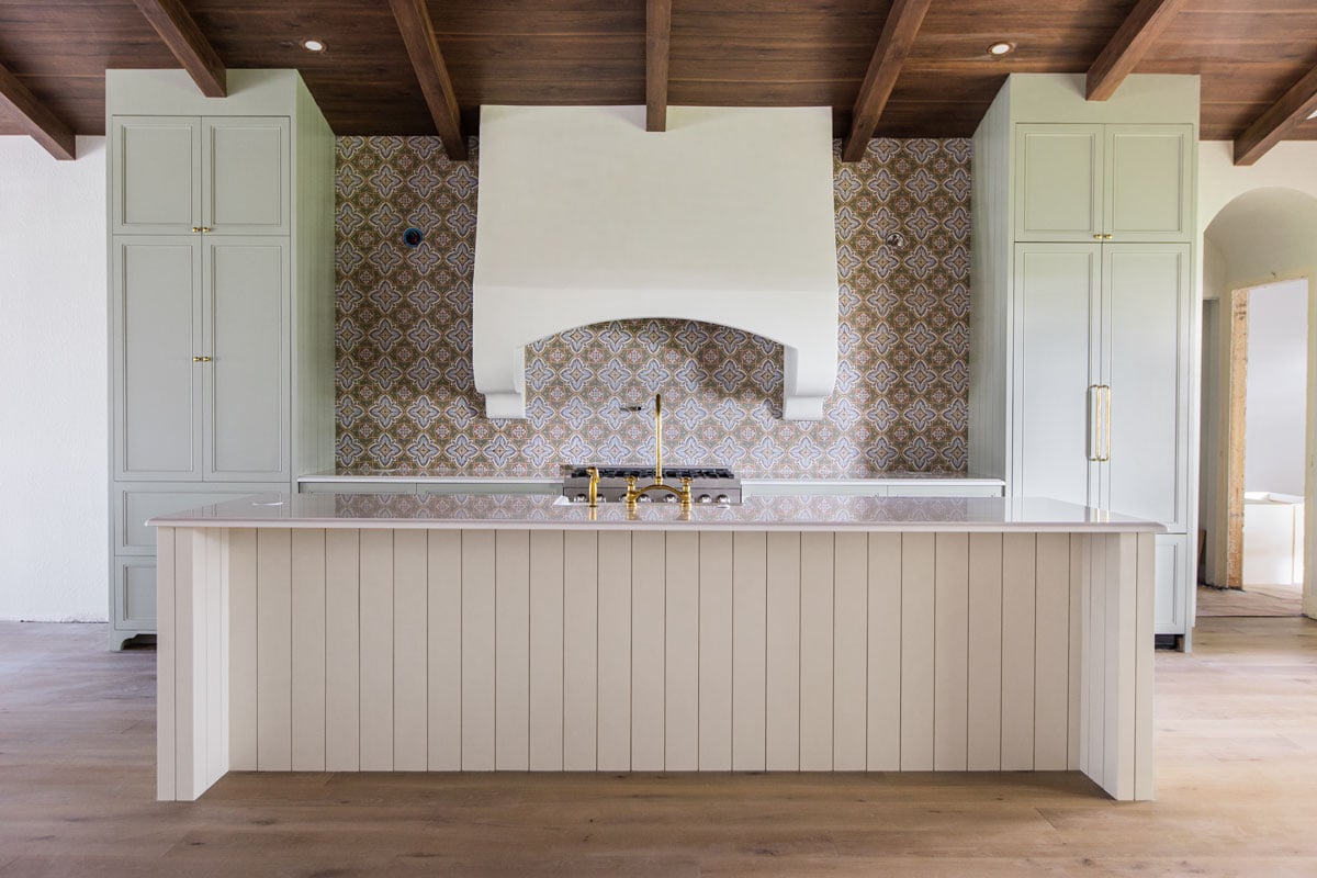 spanish style kitchen with sage green cabinets and ivory shiplap island