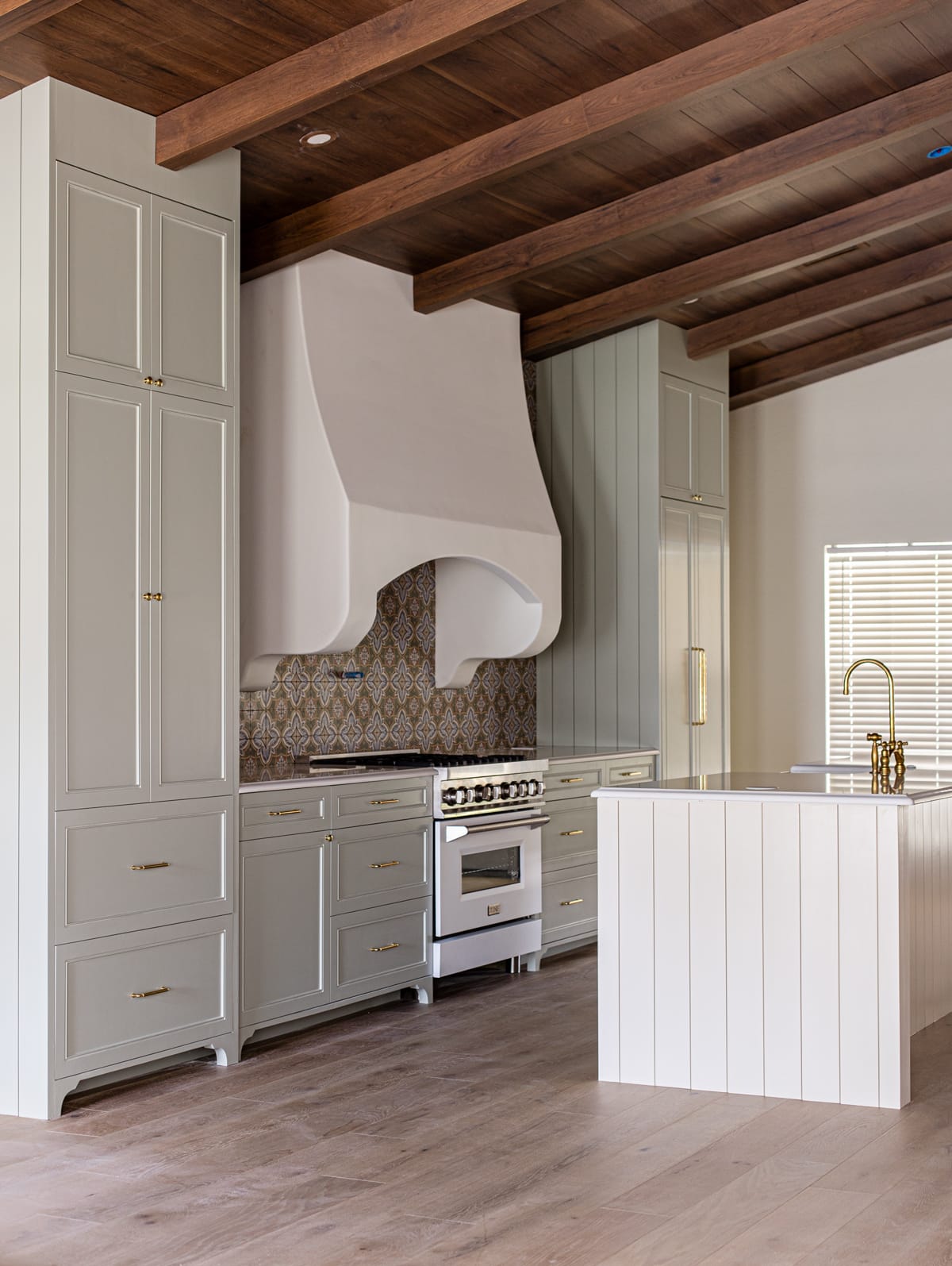 spanish style kitchen with sage green cabinets and ivory island