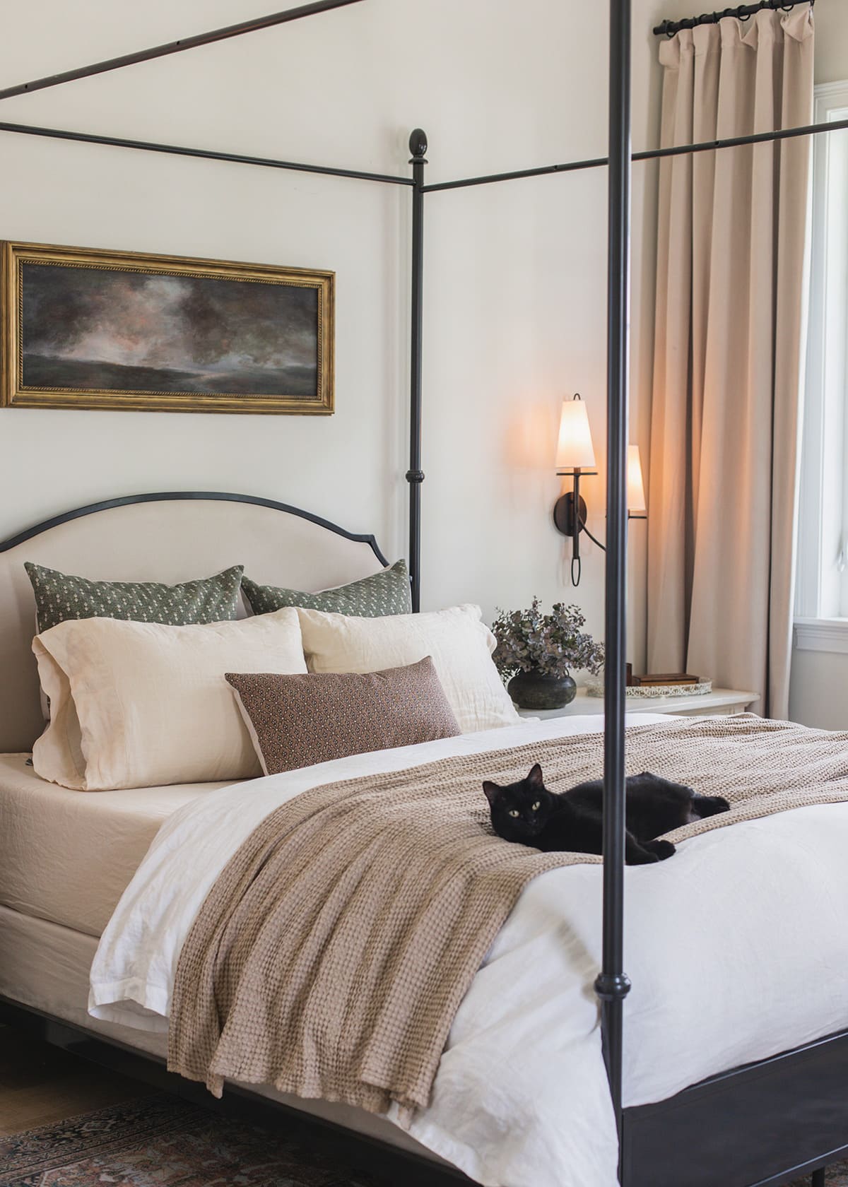 neutral bedroom with canopy bed and cat