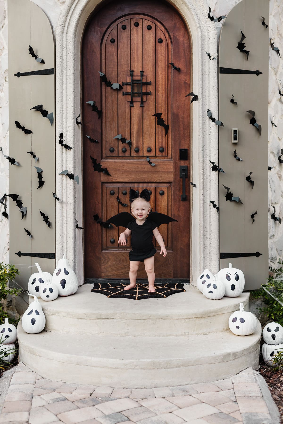 halloween front porch with bats, painted ghost pumpkins and baby dressed as bat