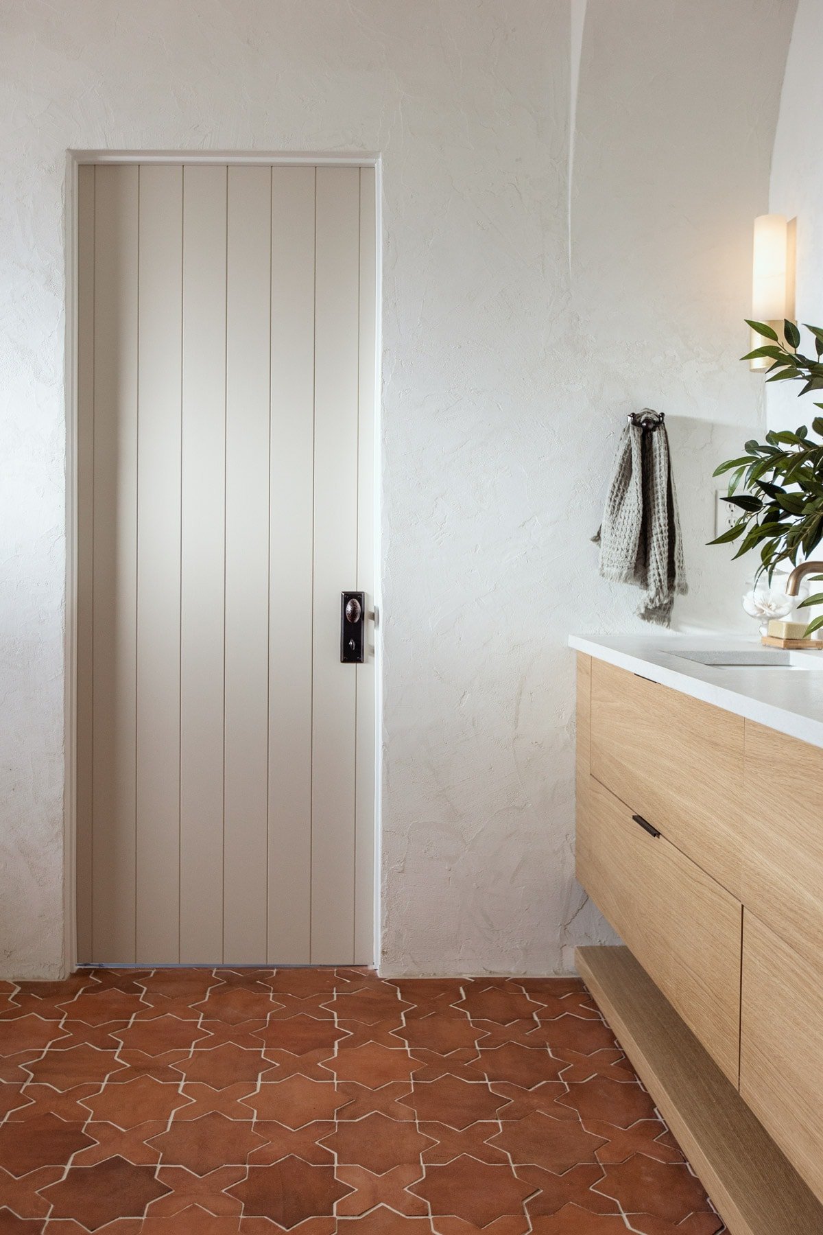 rustic mediterranean bathroom with clay tile and plank door