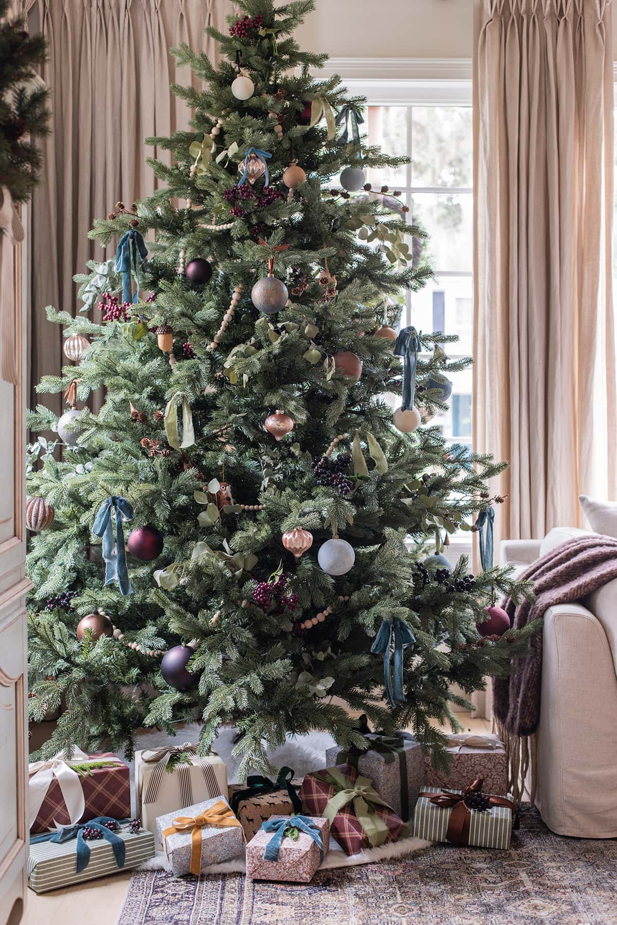 christmas tree with blue, gold, green and brown ornaments and ribbon