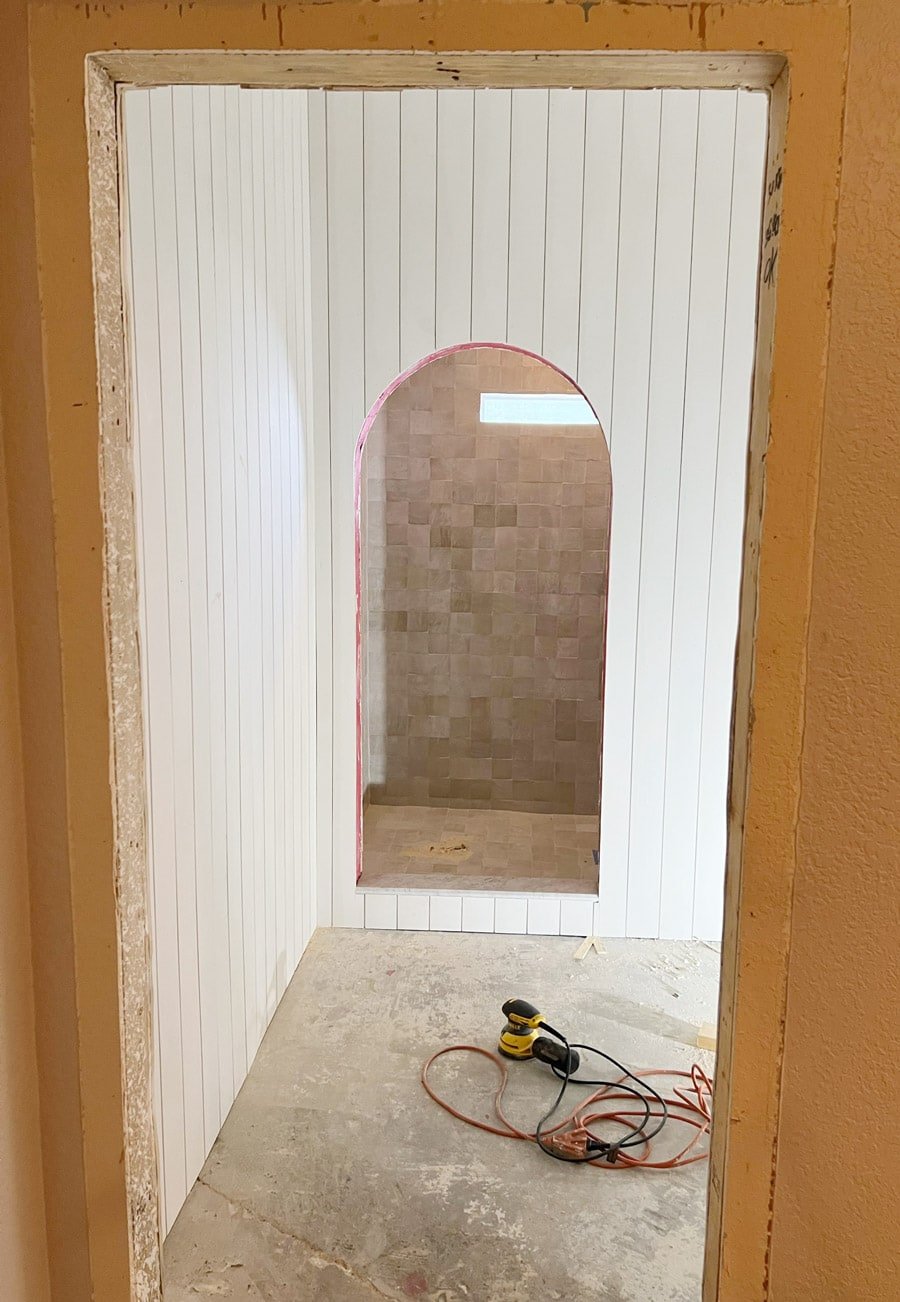 arched shower opening with shiplap walls and zellige tile