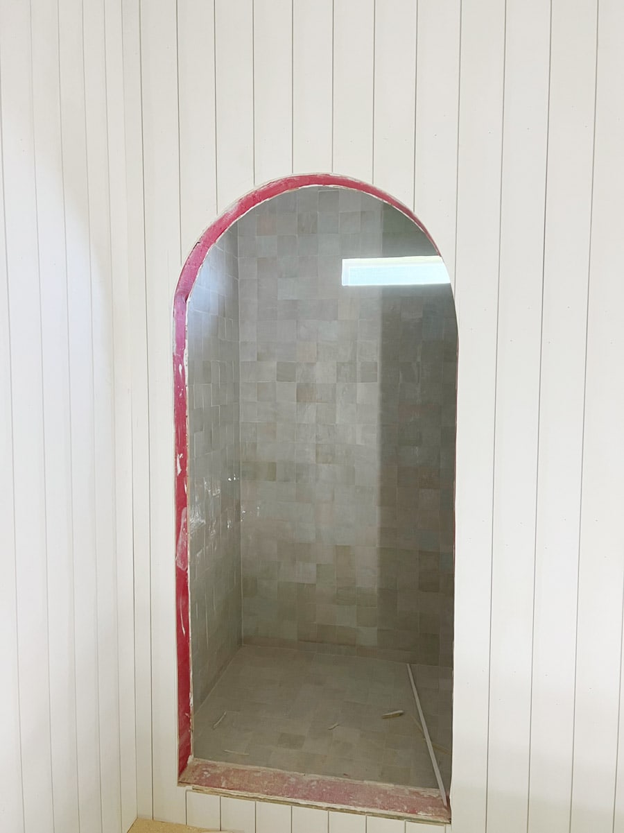 arched shower opening with shiplap walls and zellige tile