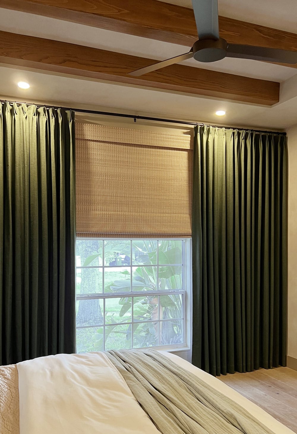 bedroom with dark green curtains, bamboo roman shade, wood ceiling beams