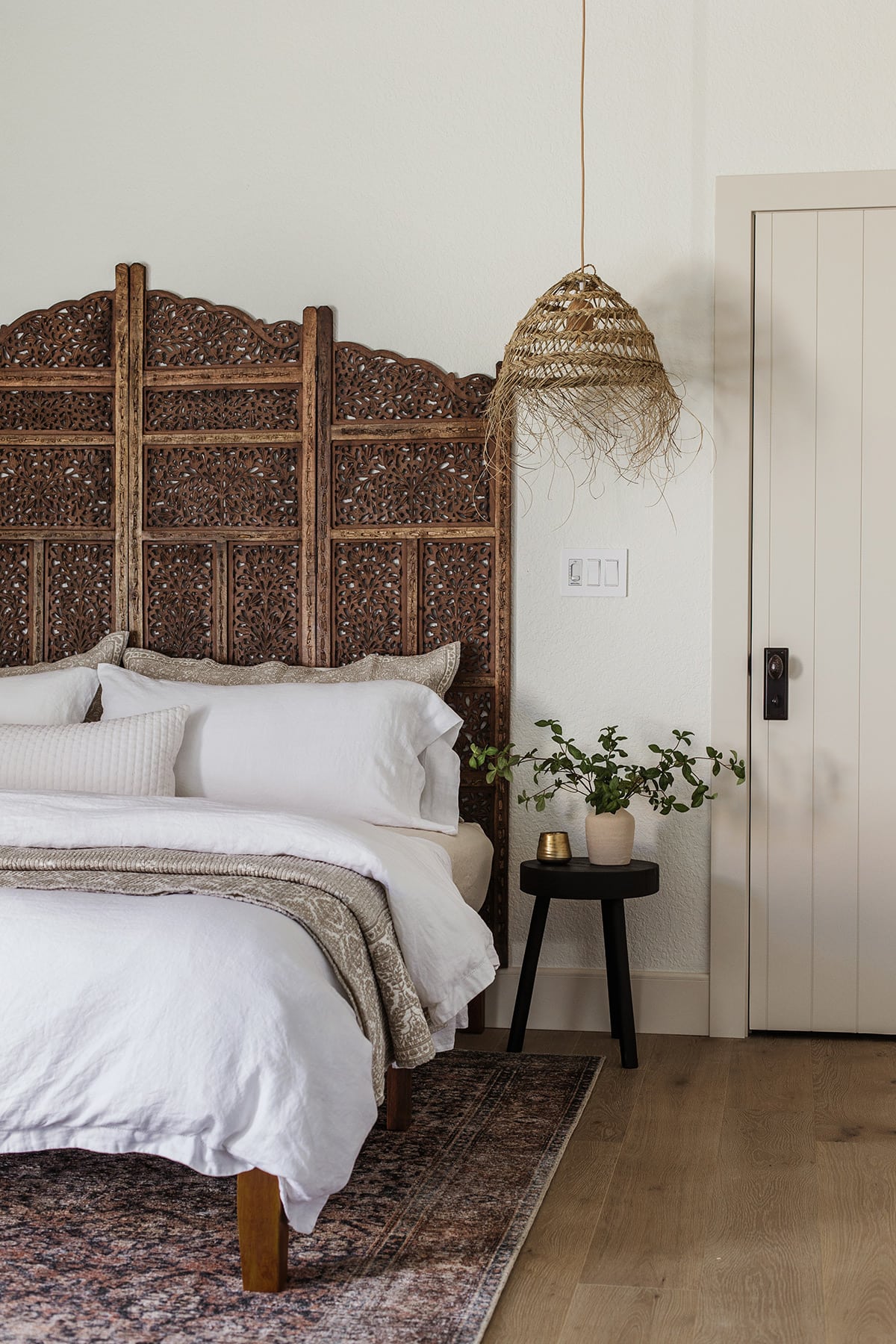 neutral moroccan bedroom with carved wood headboard and straw pendant lights