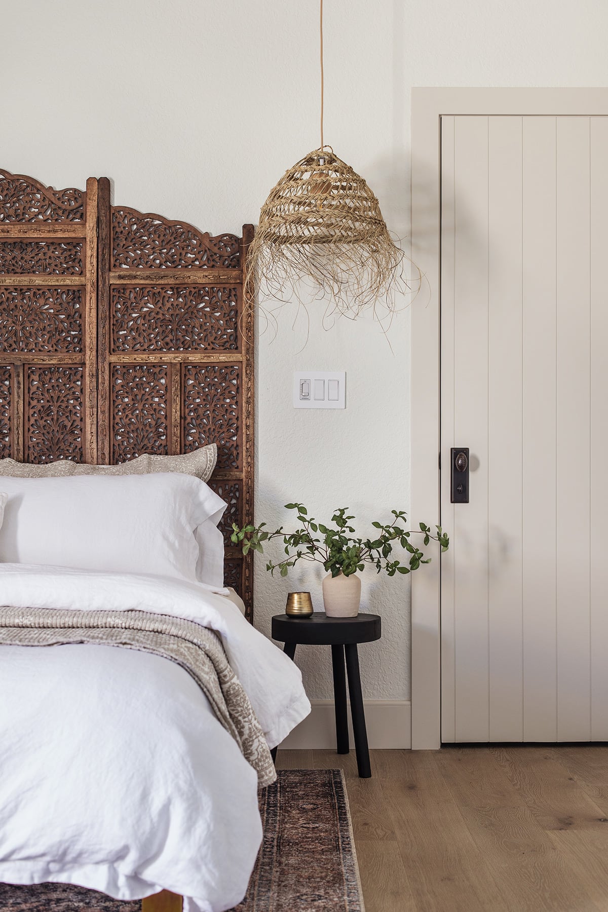 moroccan style bedroom with carved wood headboard and straw pendant lights, alabaster walls