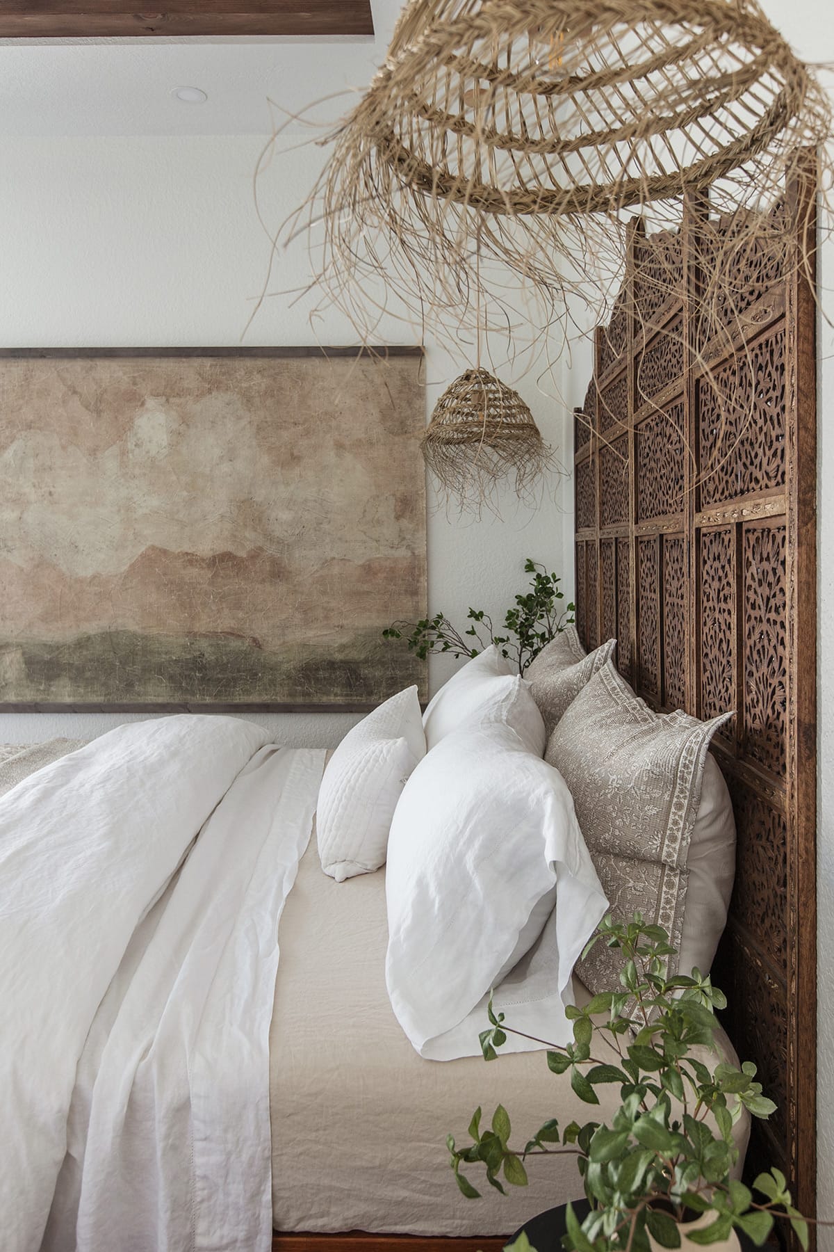 moroccan style bedroom with carved wood headboard and straw pendant lights