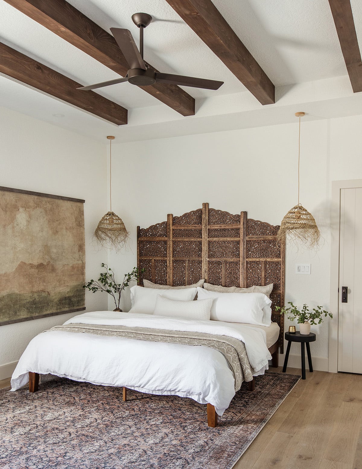 neutral bedroom with dark wood ceiling beams and alabaster paint