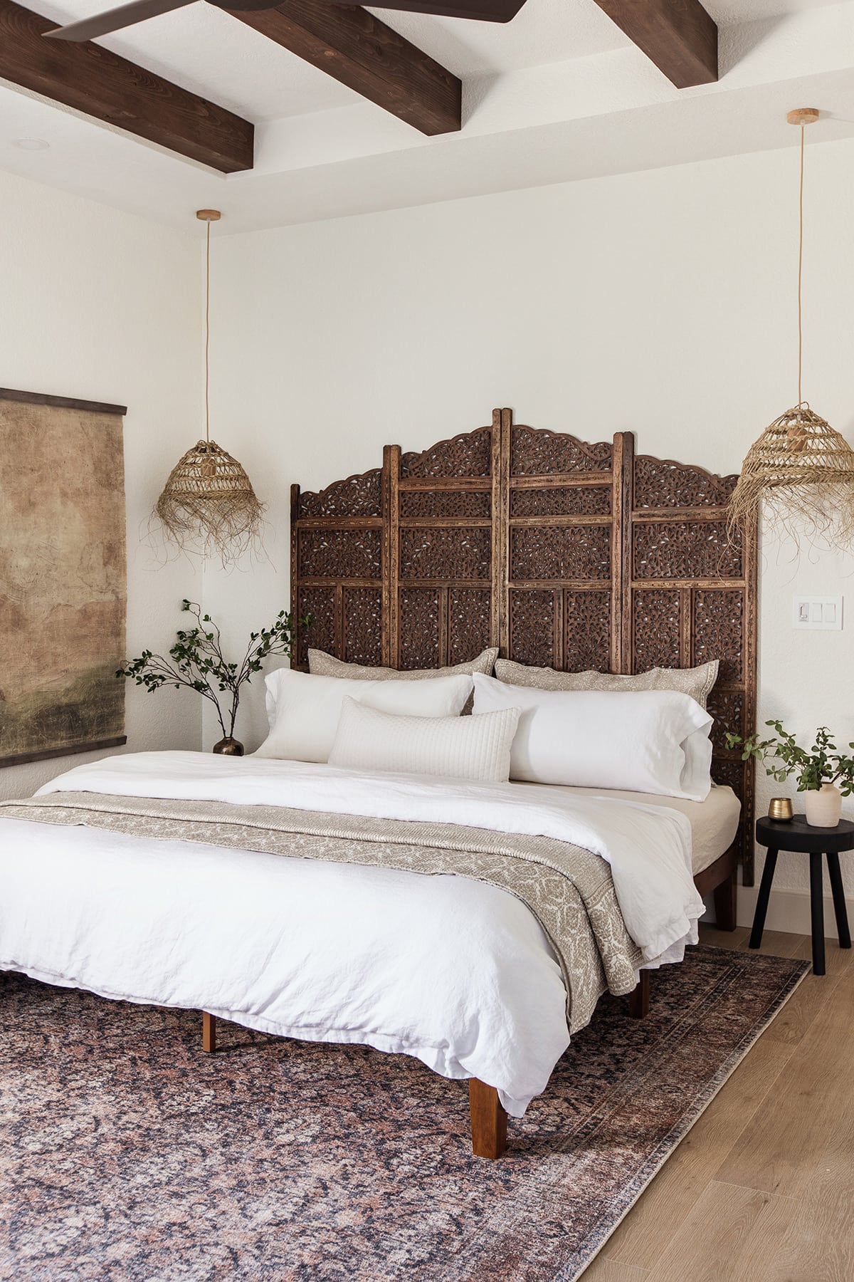 moroccan style bedroom with carved wood headboard and straw pendant lights