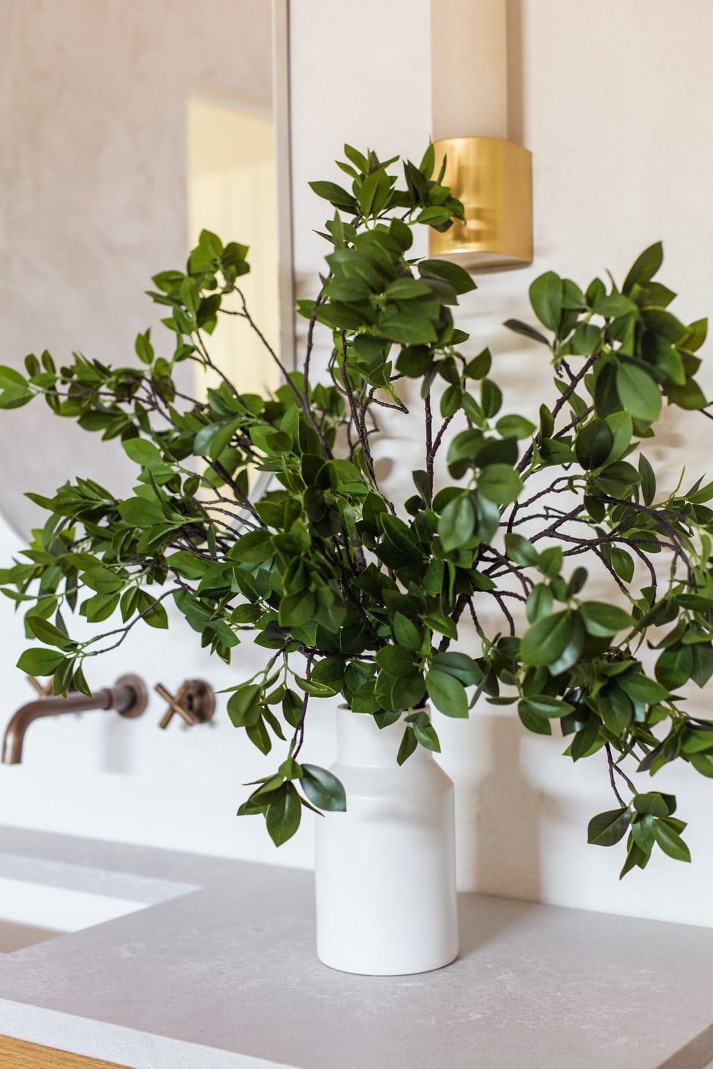 faux eucalyptus branches in vase in bathroom