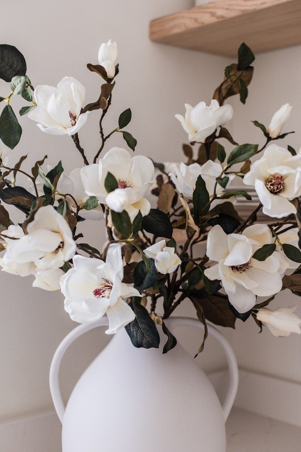 artificial magnolia branches in white vase