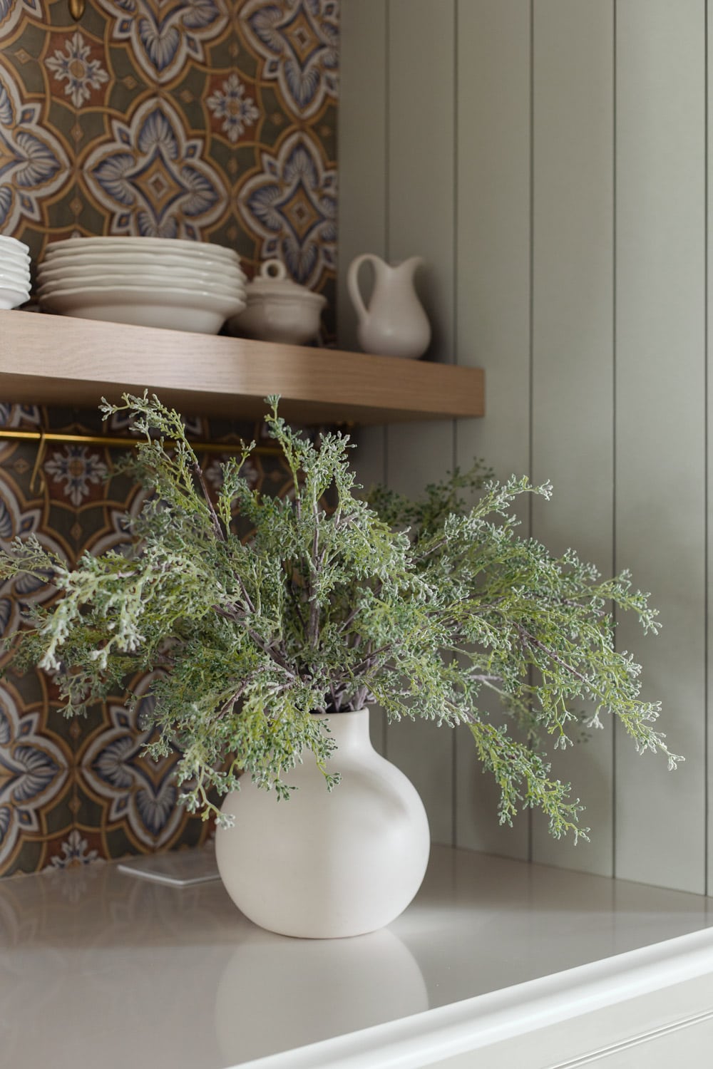 artificial seeded eucalyptus stems in vase on kitchen counter