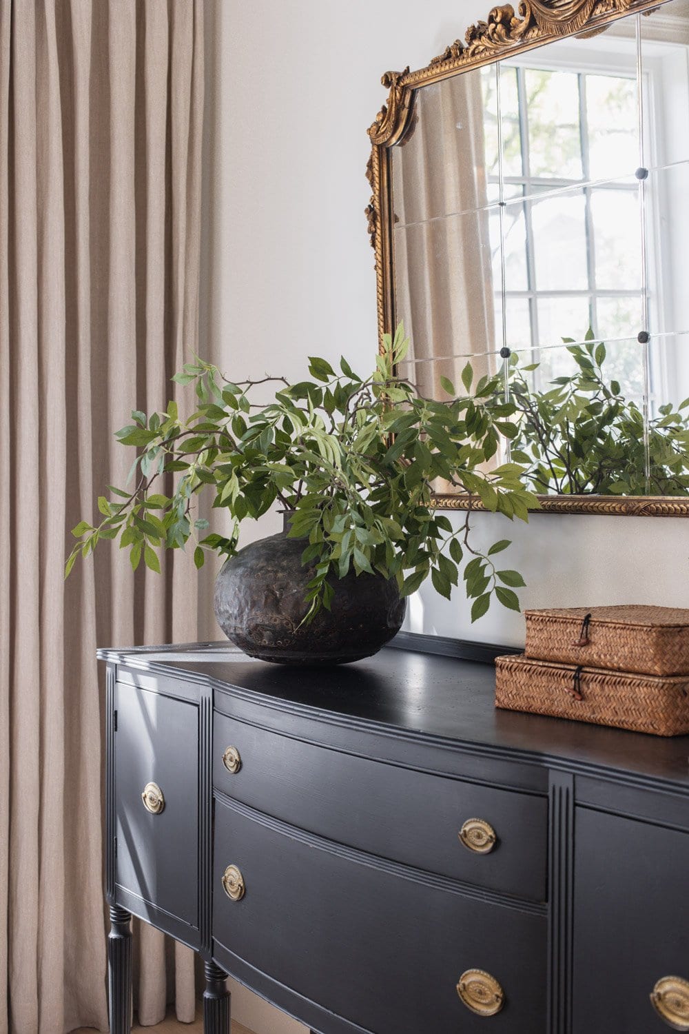 faux wisteria stems in vase on black living room cabinet