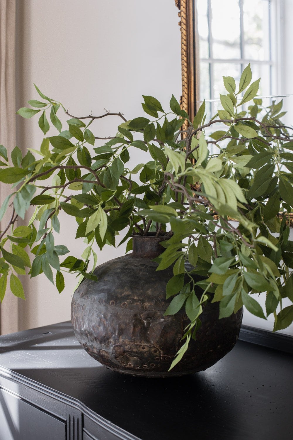 faux wisteria stems in vase on black living room cabinet