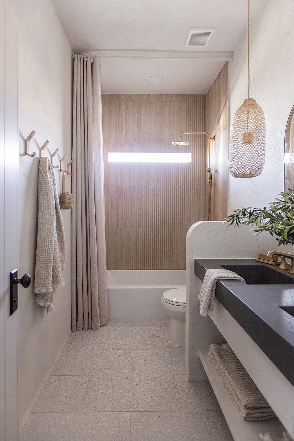 bathroom with microcement walls, wood look shower tile, custom vanity and quartz counters with integrated sinks