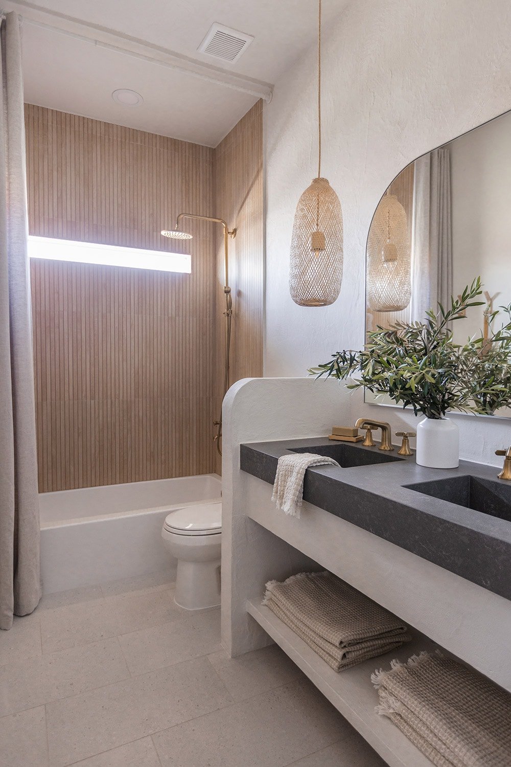 bathroom with microcement walls, wood look shower tile, custom vanity and quartz counters with integrated sinks