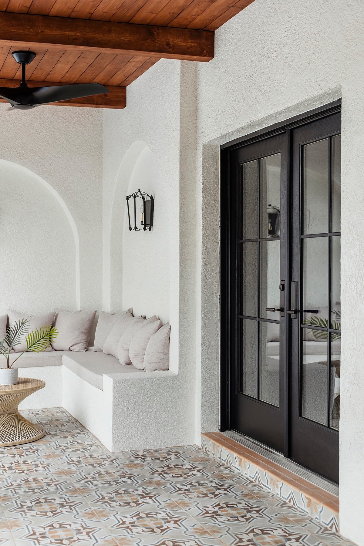 spanish style porch with wood beam ceiling, patterned tile and black french doors