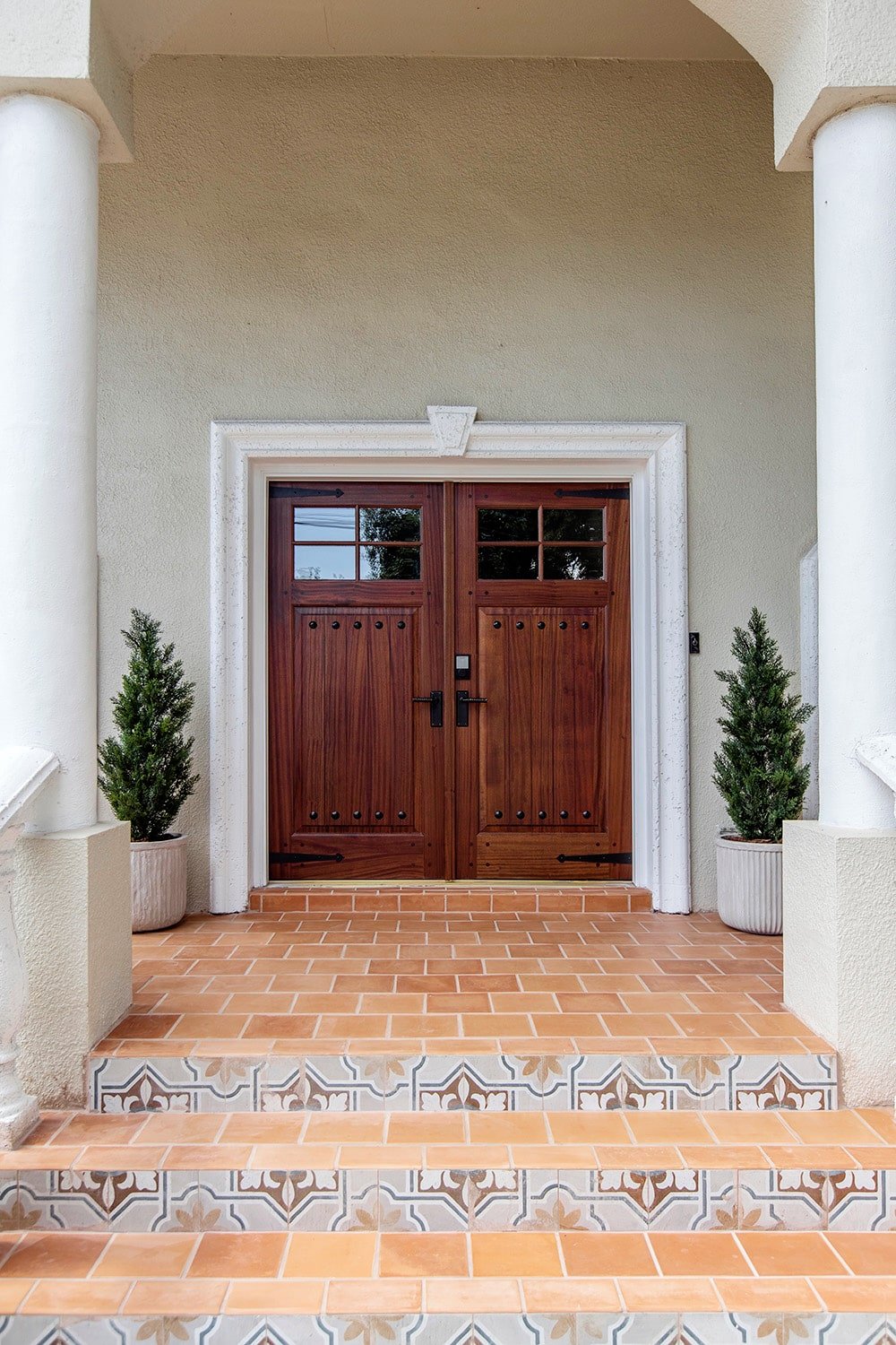 spanish style front porch with rustic wood doors and terra cotta tile