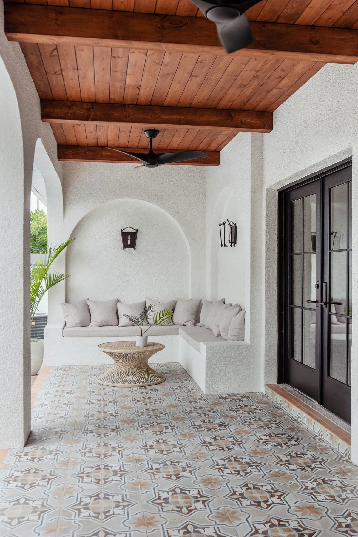 spanish style porch with wood beam ceiling, patterned tile and black french doors