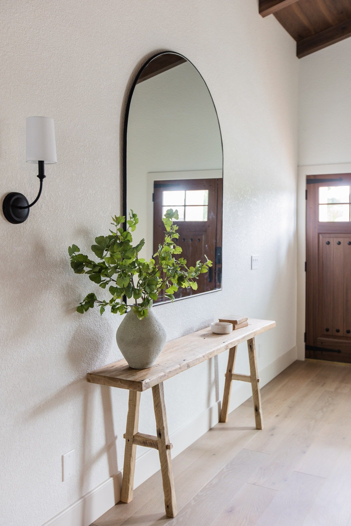 spanish style entrance with rustic wood table and arch mirror