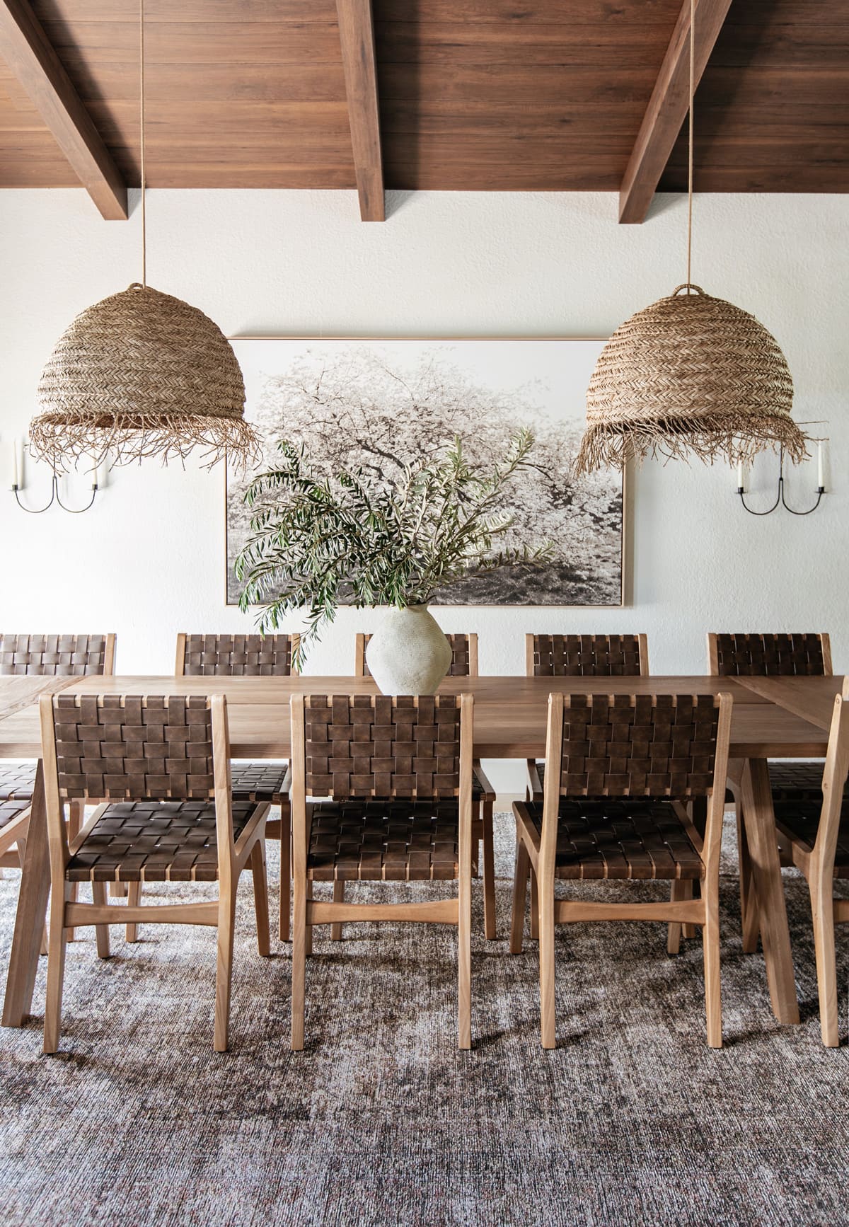 mediterranean style dining room with wood beam ceilings, large table, seagrass pendant lights