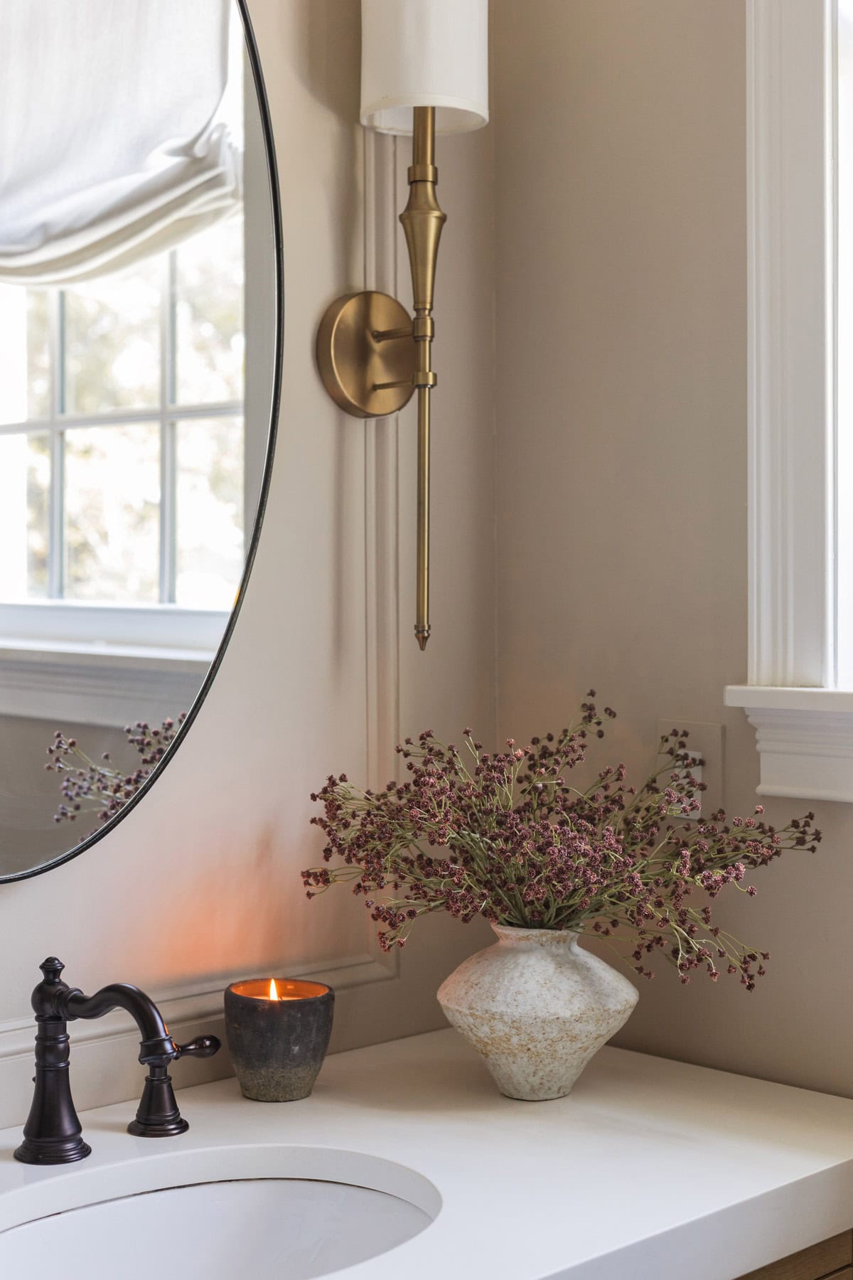 baby's breath in vase in accessible beige bathroom with candle
